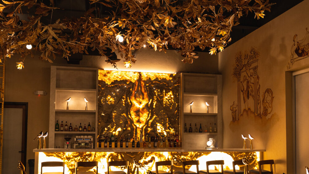 The dining room at Amami Italia, gilded branch canopy above the lit bar